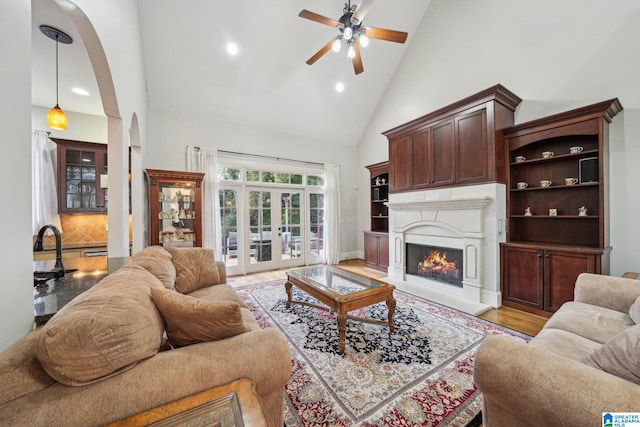 living room featuring light hardwood / wood-style floors, ceiling fan, and high vaulted ceiling