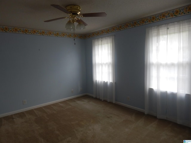 spare room with a textured ceiling, light colored carpet, and ceiling fan