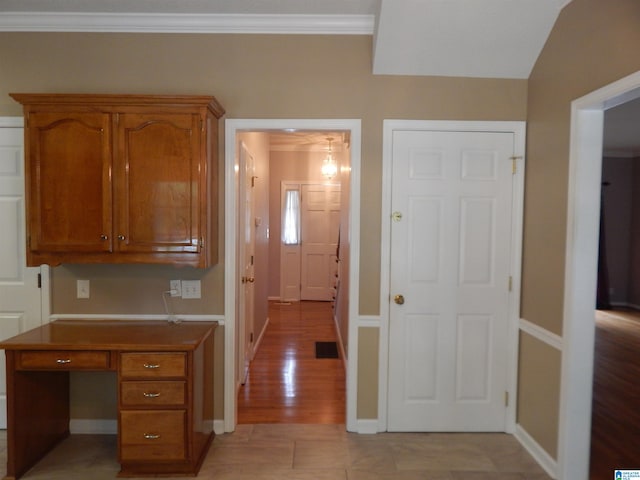 hallway featuring light wood-type flooring, lofted ceiling, and ornamental molding