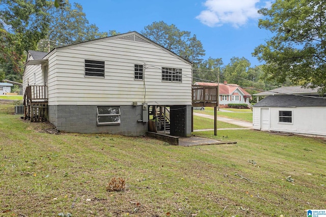 rear view of property featuring a lawn, a wooden deck, and central AC unit