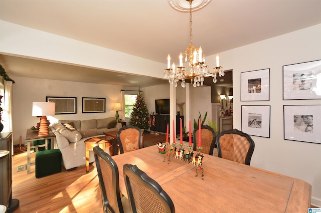 dining room with light wood-type flooring and a notable chandelier