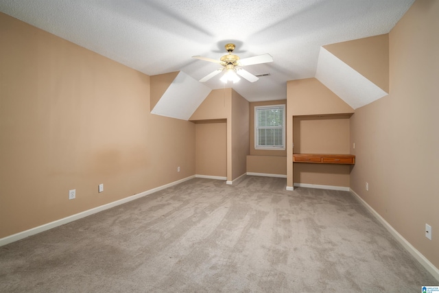 bonus room with lofted ceiling, ceiling fan, light colored carpet, and a textured ceiling