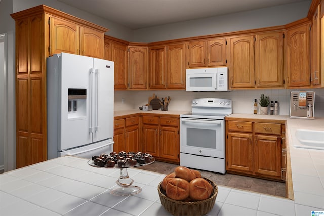 kitchen featuring decorative backsplash, white appliances, tile counters, and light tile patterned flooring