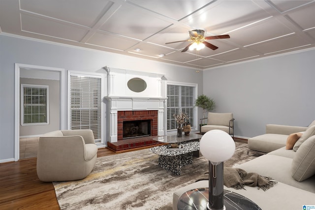 living room featuring wood-type flooring, a fireplace, coffered ceiling, and ceiling fan