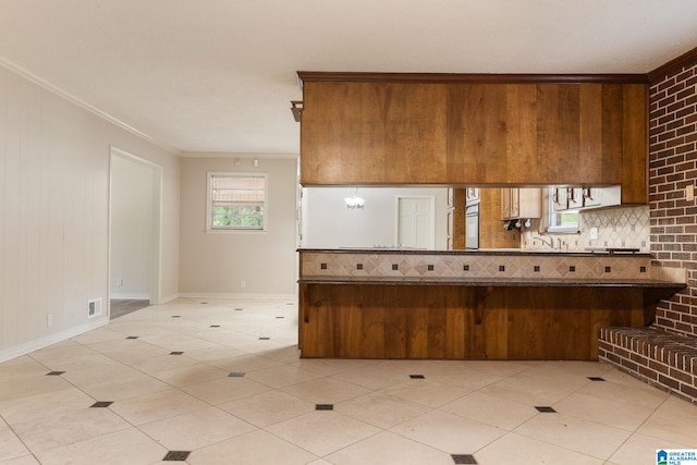 kitchen featuring backsplash, a peninsula, crown molding, and visible vents