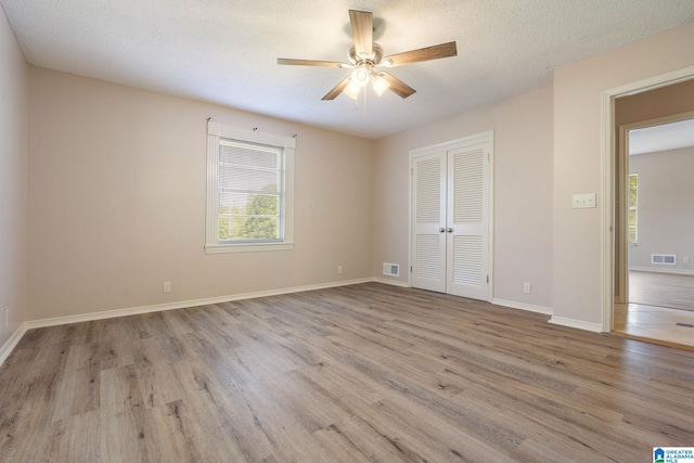 spare room with ceiling fan, a textured ceiling, and light wood-type flooring