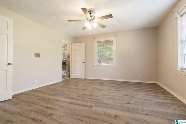 empty room featuring a textured ceiling, wood-type flooring, and ceiling fan