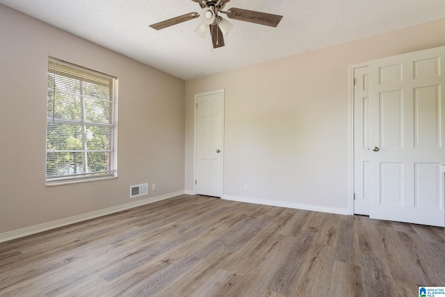 unfurnished bedroom featuring ceiling fan, a textured ceiling, and light hardwood / wood-style floors