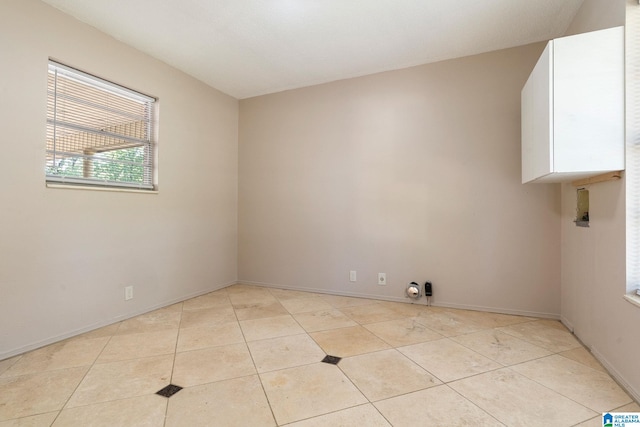 spare room featuring light tile patterned floors and baseboards