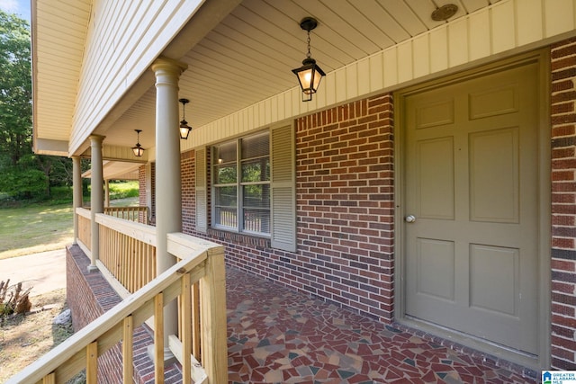 property entrance with covered porch, brick siding, and a garage