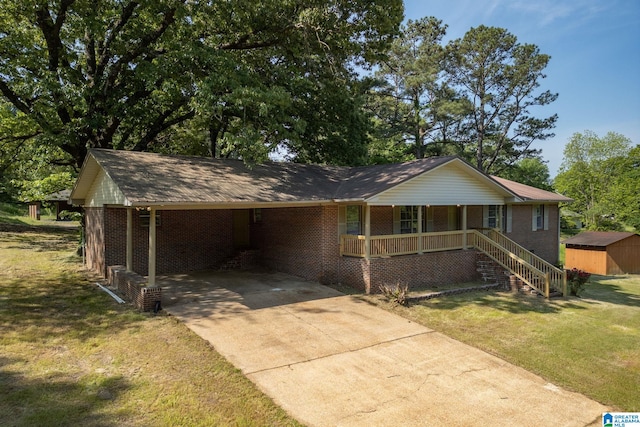 view of front facade with a front yard, an attached carport, brick siding, driveway, and a porch