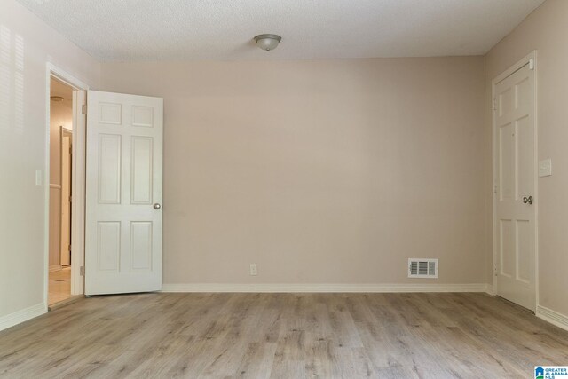 spare room featuring a textured ceiling and light hardwood / wood-style flooring