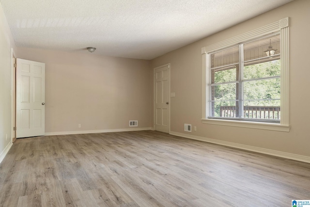 spare room featuring a textured ceiling and light hardwood / wood-style flooring