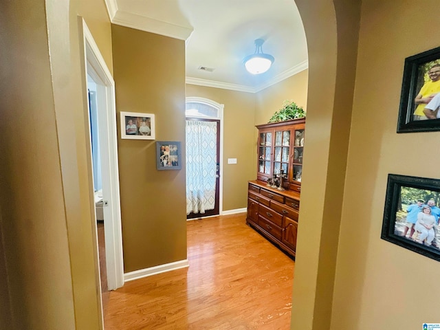 corridor with light hardwood / wood-style flooring and ornamental molding