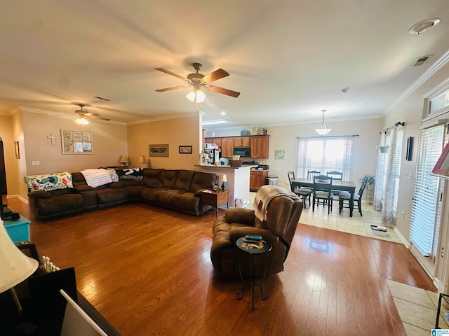 living room featuring ornamental molding, light hardwood / wood-style floors, and ceiling fan