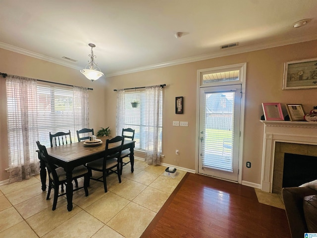 dining room featuring light hardwood / wood-style flooring, a tile fireplace, and plenty of natural light