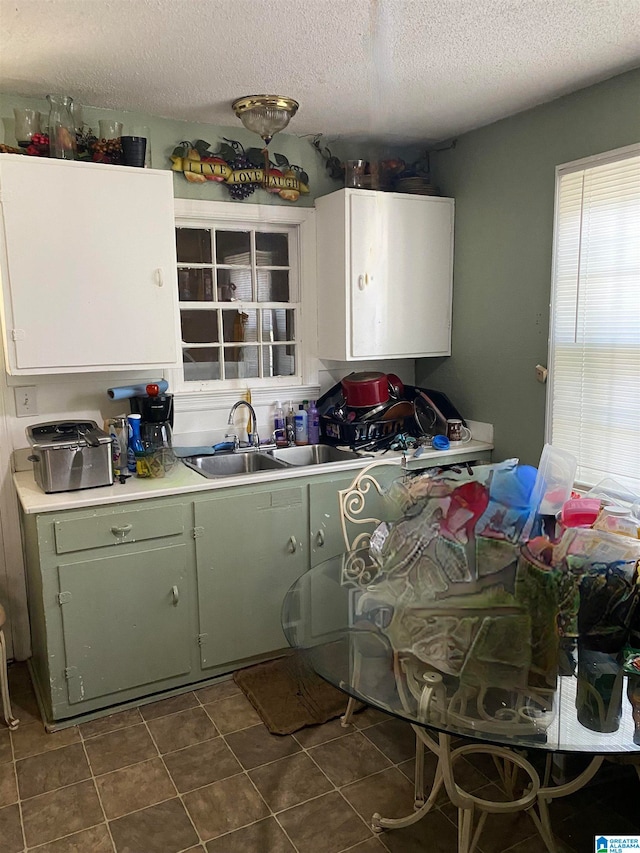 kitchen with green cabinets, a textured ceiling, sink, and dark tile patterned floors