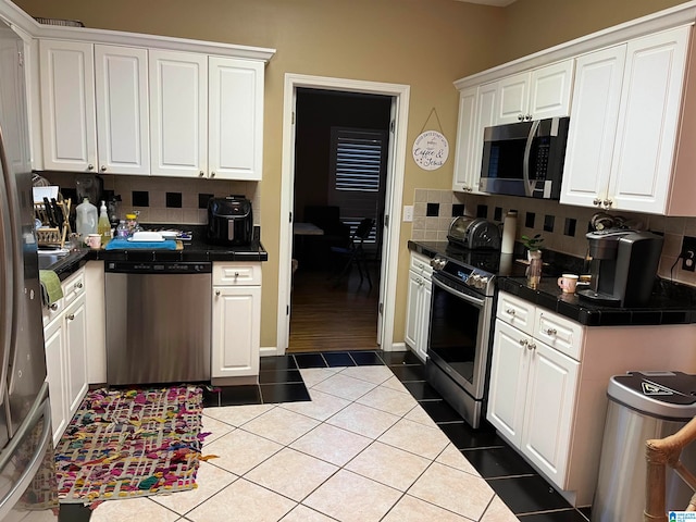 kitchen featuring white cabinetry, light tile patterned floors, stainless steel appliances, and tasteful backsplash