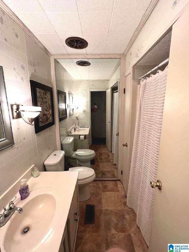 bathroom with tile walls, a shower with shower curtain, ornamental molding, vanity, and toilet