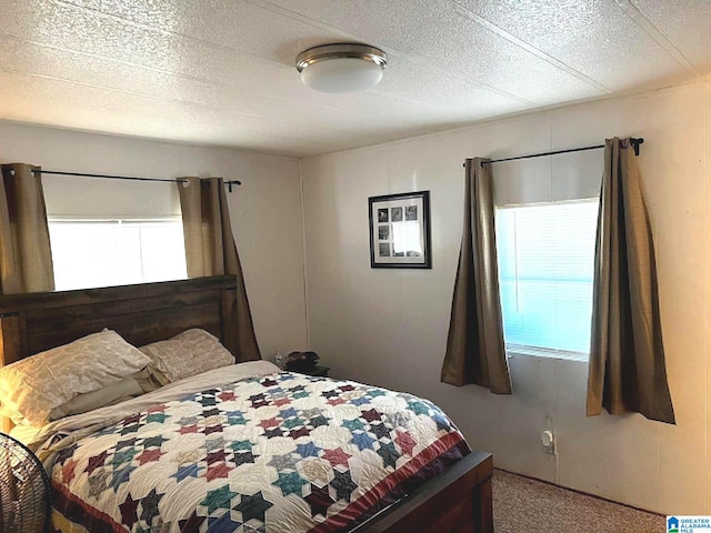 bedroom with multiple windows, carpet flooring, and a textured ceiling