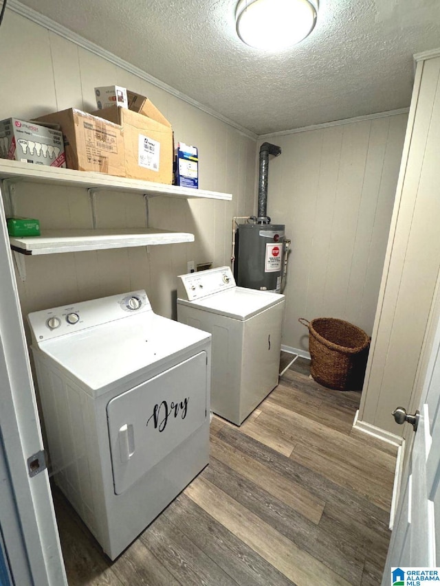 washroom featuring dark wood-type flooring, gas water heater, wood walls, a textured ceiling, and washing machine and clothes dryer