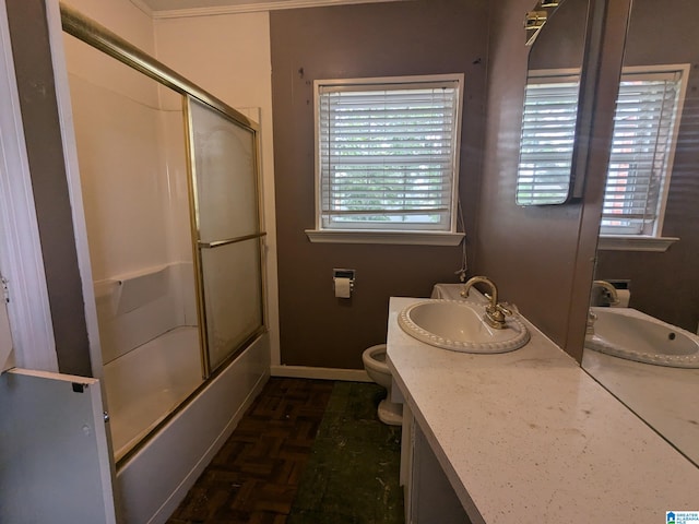 full bathroom with a wealth of natural light, combined bath / shower with glass door, vanity, and toilet