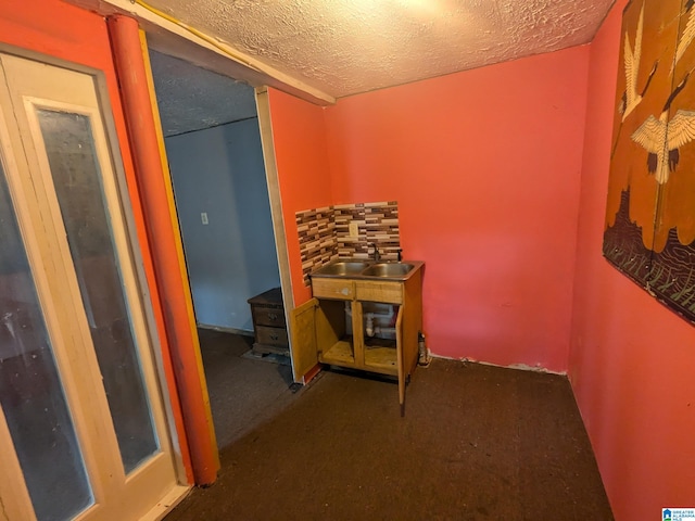 hall featuring dark colored carpet and a textured ceiling