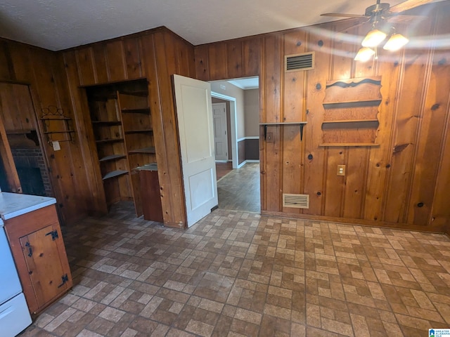 kitchen featuring ceiling fan, a textured ceiling, and wooden walls