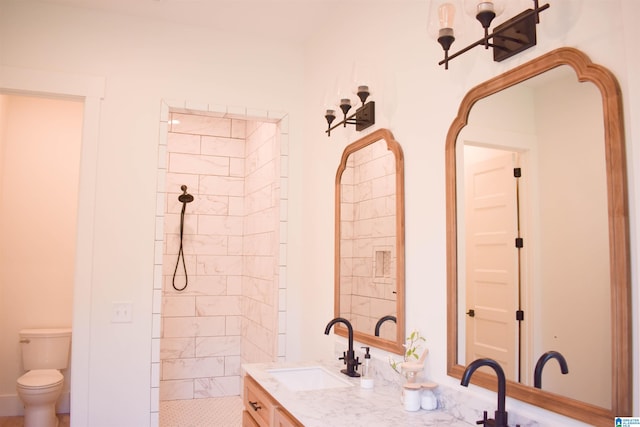 bathroom featuring tiled shower, vanity, and toilet