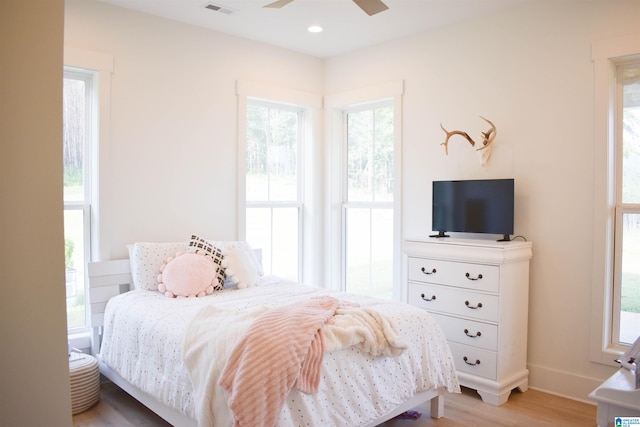 bedroom featuring ceiling fan, light hardwood / wood-style flooring, and multiple windows