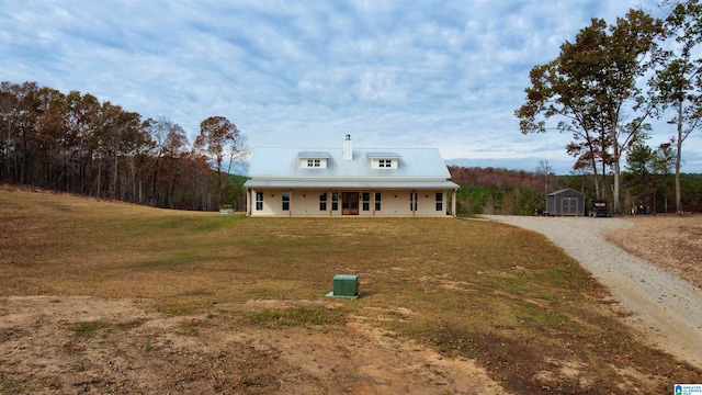 view of front facade with a front lawn, covered porch, and a shed