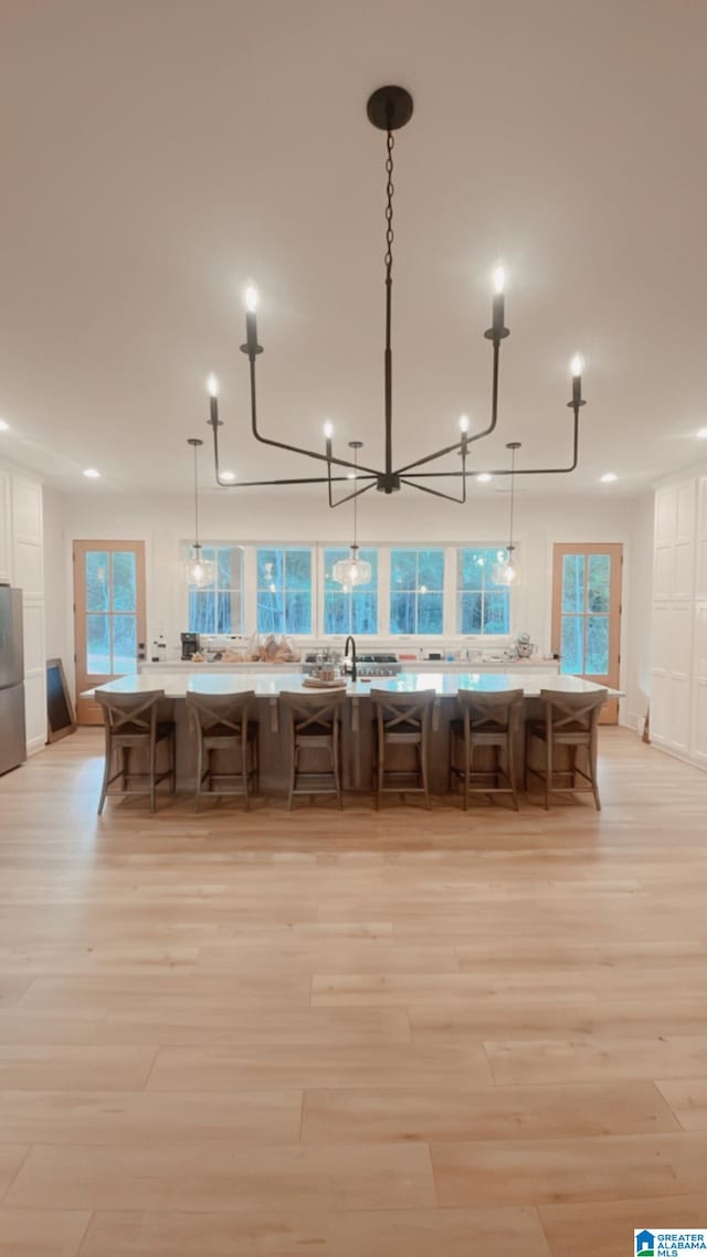 kitchen with light hardwood / wood-style floors, hanging light fixtures, a healthy amount of sunlight, and stainless steel fridge