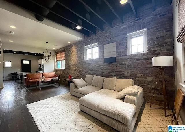 living room featuring wood-type flooring, beamed ceiling, and brick wall