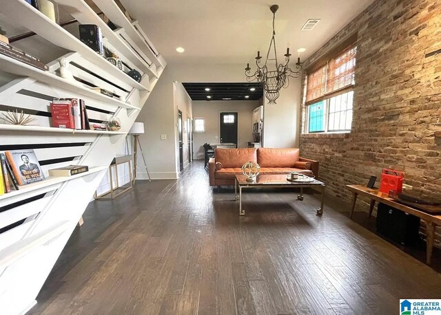 living room featuring recessed lighting, an inviting chandelier, brick wall, baseboards, and hardwood / wood-style floors
