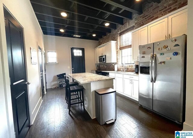 kitchen featuring dark wood-style flooring, appliances with stainless steel finishes, a kitchen island, and plenty of natural light
