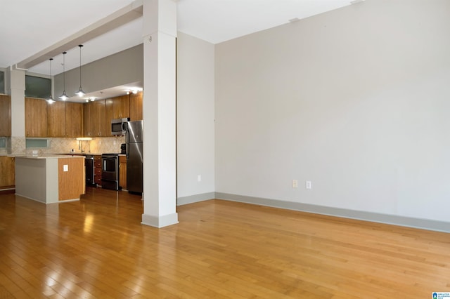 kitchen with a kitchen breakfast bar, hanging light fixtures, tasteful backsplash, light hardwood / wood-style floors, and stainless steel appliances