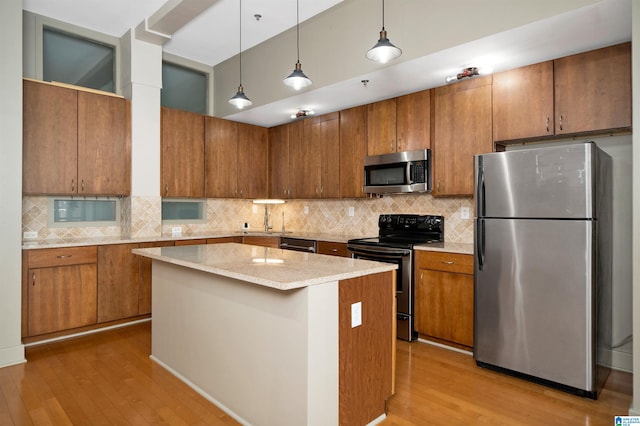 kitchen featuring a center island, stainless steel appliances, tasteful backsplash, pendant lighting, and light wood-type flooring