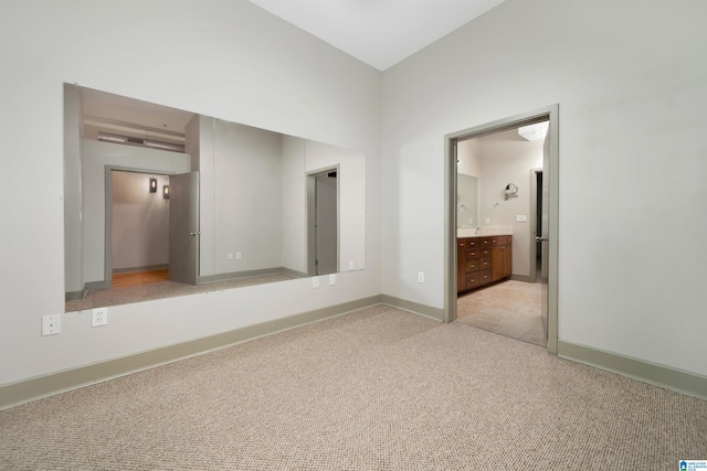 unfurnished bedroom featuring light colored carpet and ensuite bath