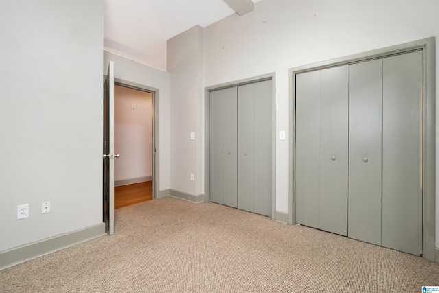 unfurnished bedroom featuring light carpet and multiple closets