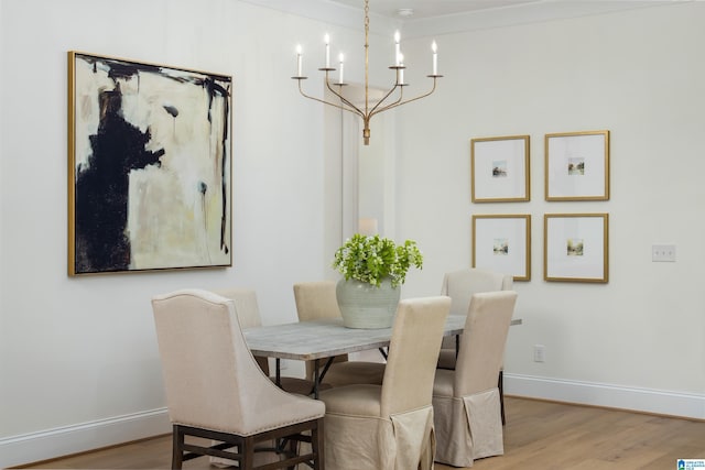 dining area featuring a chandelier, baseboards, and wood finished floors