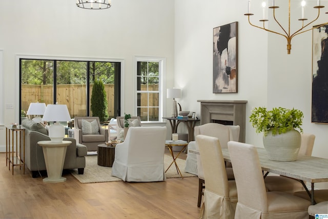 living room featuring a towering ceiling, a fireplace, an inviting chandelier, and wood finished floors