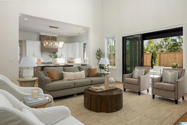 living area featuring recessed lighting, light wood-style floors, a high ceiling, and crown molding