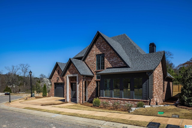 view of front of property featuring a sunroom, concrete driveway, an attached garage, a shingled roof, and brick siding