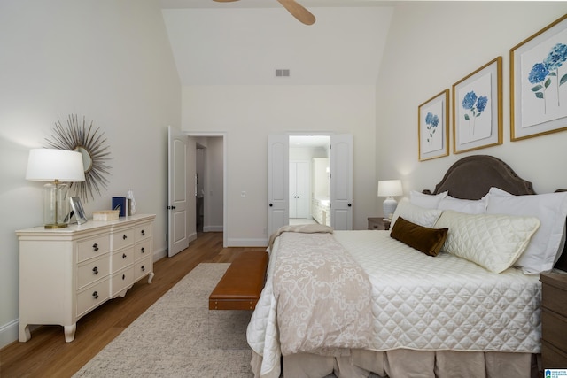 bedroom featuring visible vents, baseboards, high vaulted ceiling, and wood finished floors