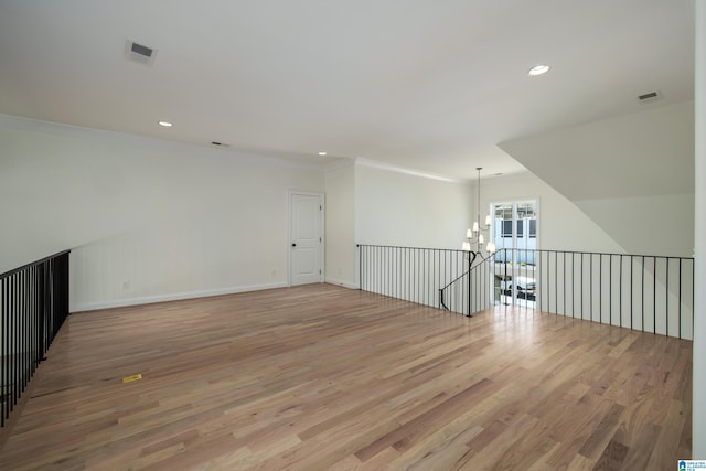 empty room featuring recessed lighting, light wood-style flooring, a chandelier, and ornamental molding