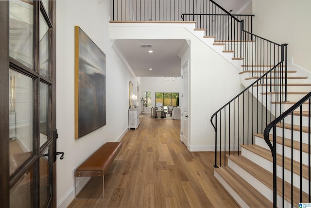 entrance foyer featuring visible vents, stairway, baseboards, and wood finished floors