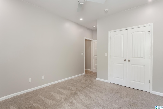 unfurnished bedroom featuring ceiling fan, light colored carpet, and a closet