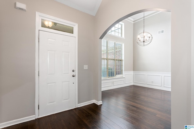 foyer with crown molding, dark wood-type flooring, and a chandelier