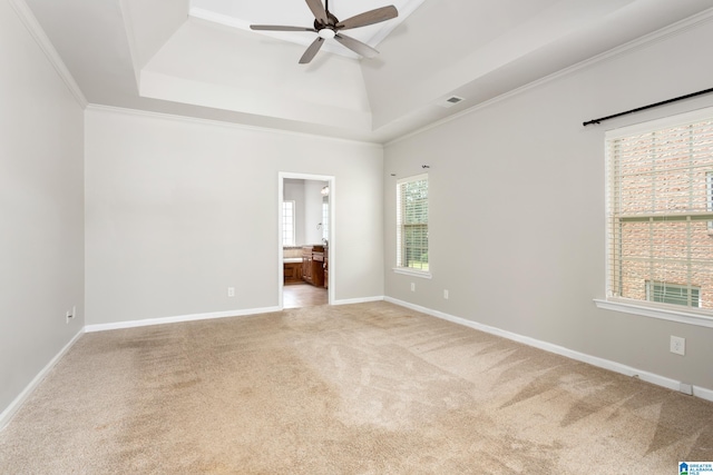 unfurnished room with a raised ceiling, ceiling fan, light colored carpet, and crown molding