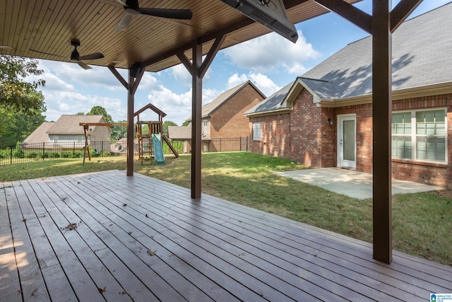 wooden terrace featuring a lawn, ceiling fan, a patio area, and a playground